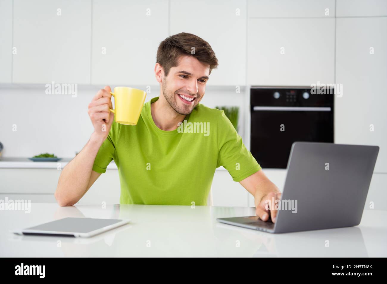 Portrait Foto Mann mit Laptop sitzt in der Küche Kaffee zu Hause trinken Stockfoto