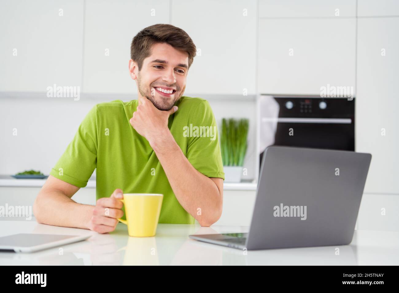 Portrait Foto Mann mit Laptop sitzen in der Küche Kaffee trinken arbeiten Remote Idee Stockfoto