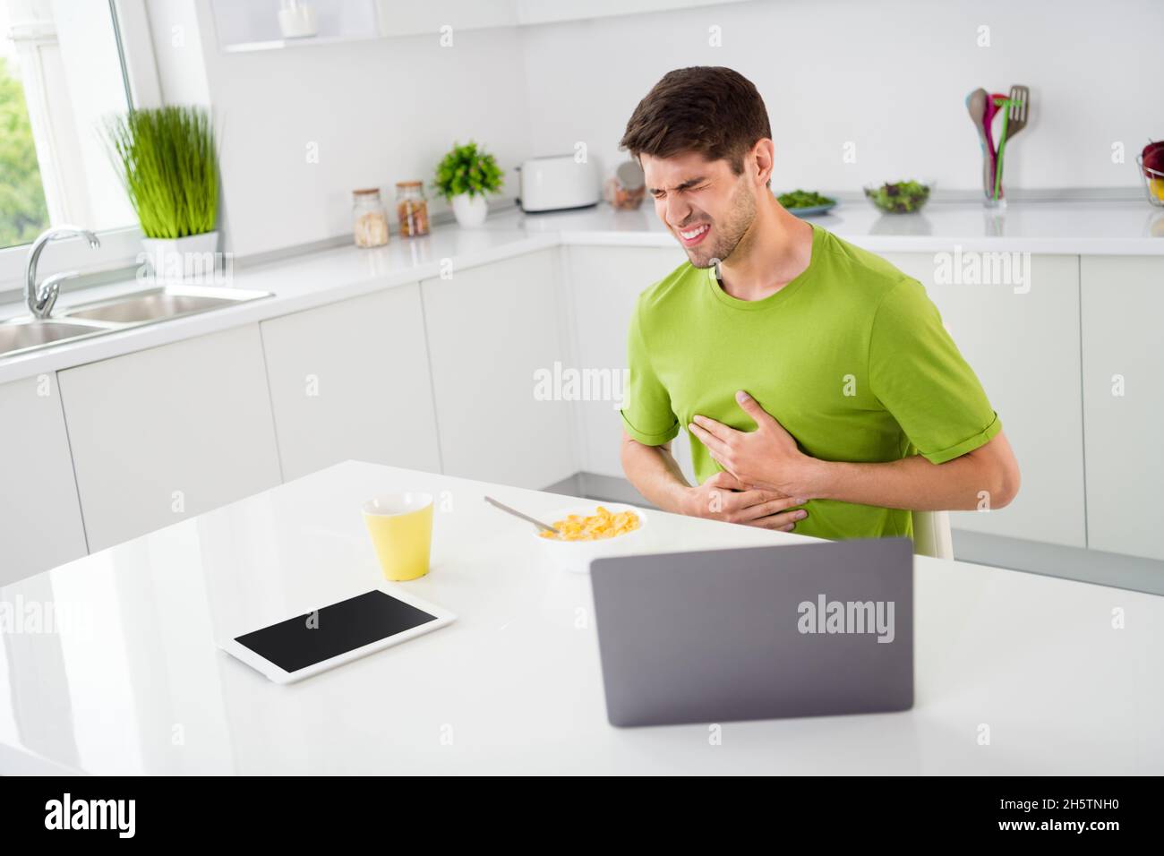 Portrait Foto Mann mit Laptop leiden unter Bauchschmerzen beim Frühstück Stockfoto