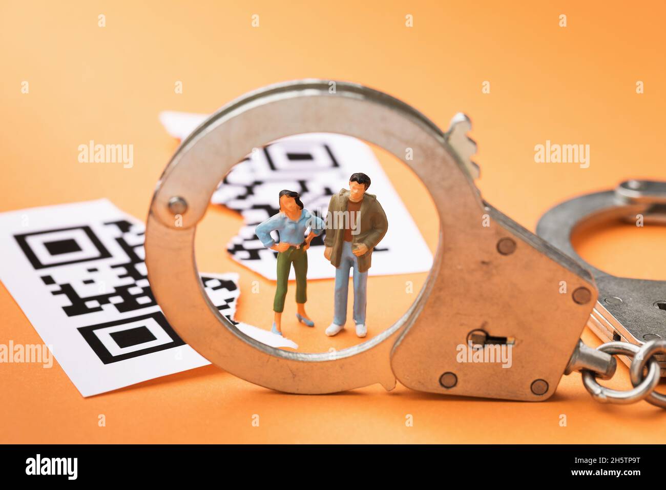 Plastikspielzeug Männer, Handschellen und in der Hälfte zerrissen QRCode auf einem farbigen