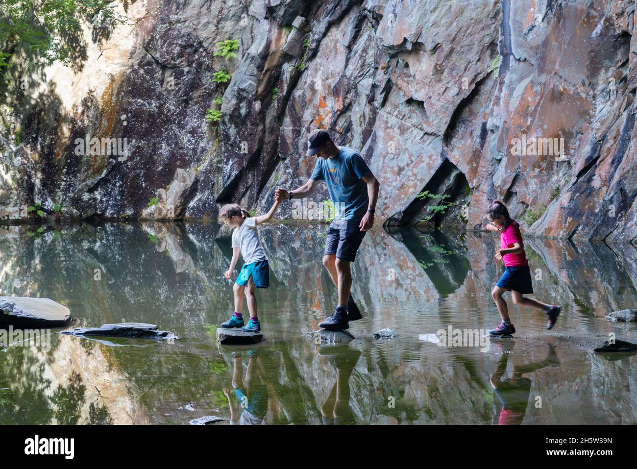 Familienurlaub Großbritannien - ein Vater und Kinder auf den Trittsteinen, Rydal Cave, Rydal, Lake District National Park, Cumbria England Großbritannien Stockfoto