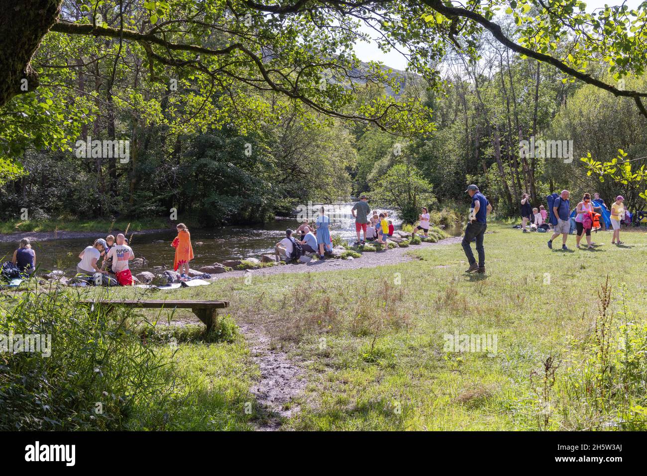 Aufenthalt in Großbritannien; Menschen und Familien, die am Ufer des Flusses Rothay in der Nähe des Wassersees Rydal sitzen, während der Sommerferien im Lake District Cumbria in Großbritannien; Stockfoto