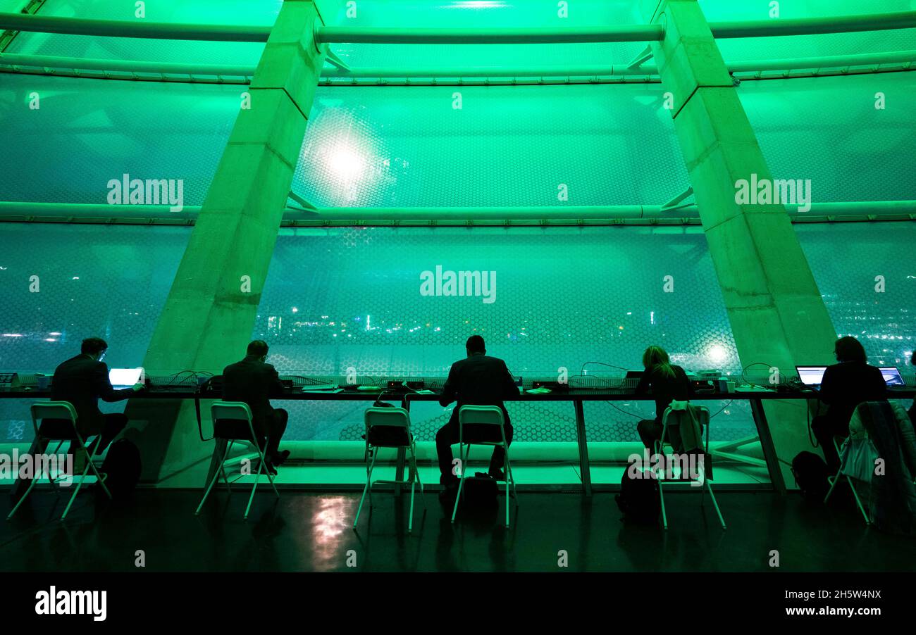 Glasgow, Schottland, Großbritannien. November 2021. Tag zwölf des Klimagipfels um COP26 in Glasgow. PIC; Delegierte der COP26, die an Fenstern von OVO Hydro in der Active Zone arbeiten, werden von der Außenbeleuchtung in grünes Licht getaucht. Iain Masterton/Alamy Live News. Stockfoto