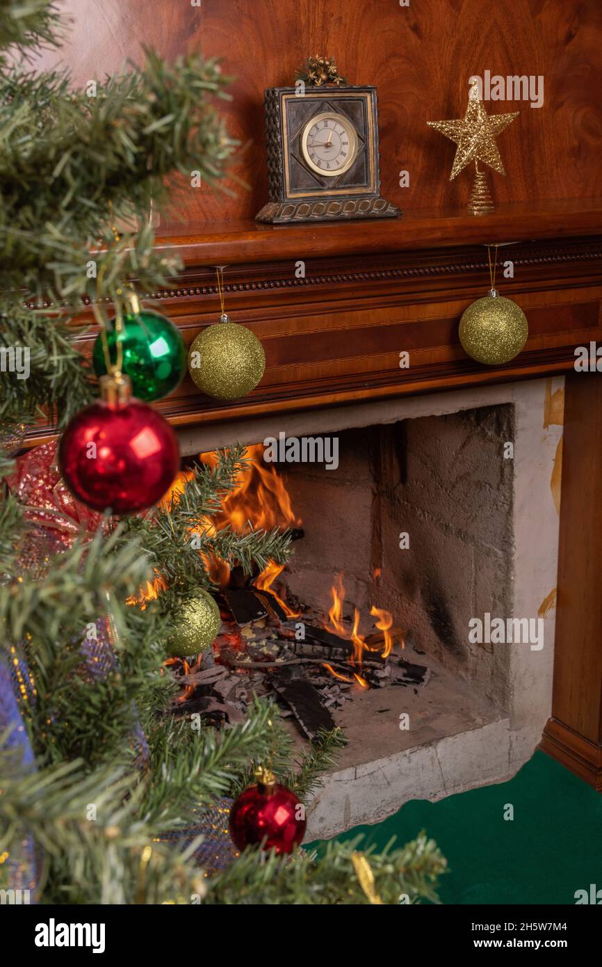 Inneneinrichtung, Haus mit gemütlichem Kamin mit Kamin mit einer Uhr und Stern neben einem Weihnachtsbaum mit farbigen Kugeln verziert, Urlaub Stockfoto