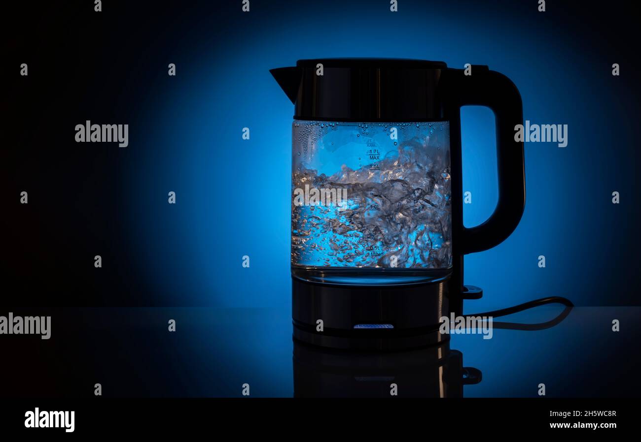 Glaskessel mit Wasser gefüllt, während sie kochte. Auf einem blauen konzeptionellen Hintergrund. Stockfoto