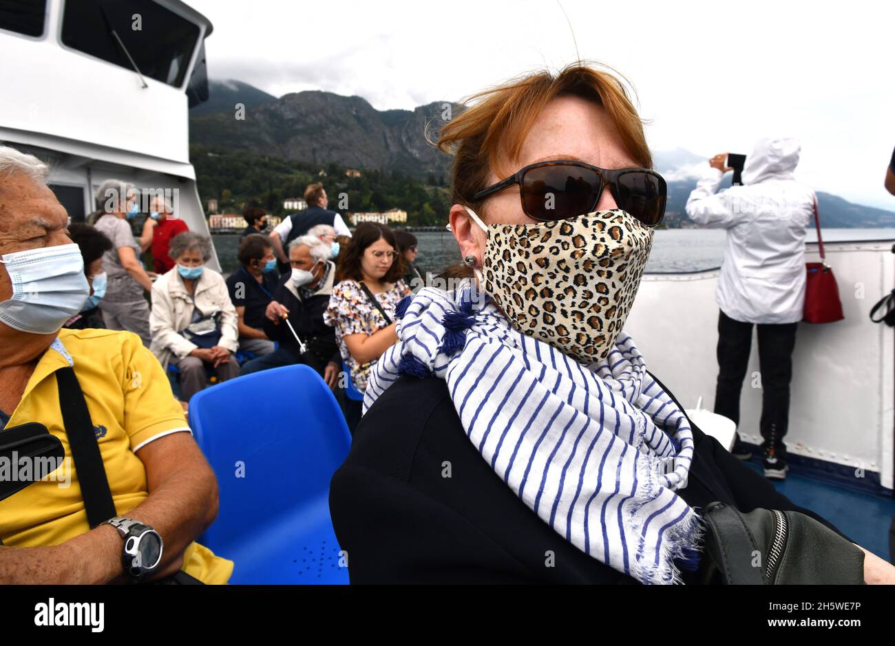 Passagiere Touristen mit Covid 19 Virus Pandemie Gesichtsmasken auf dem Comer See Passagierboot in Italien 2021 Stockfoto