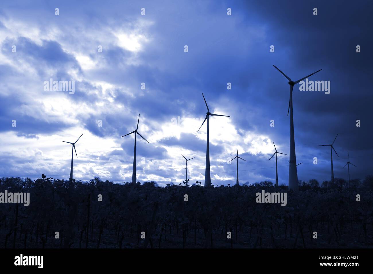 Windmühlen, die Strom produzieren, werden in einem dunkelblauen Himmel dargestellt Stockfoto
