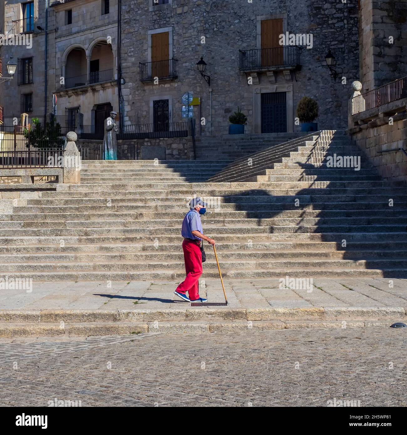 Ein alter Mann, der langsam mit seinem Stock auf der Plaza Mayor von Trujillo geht. Stockfoto