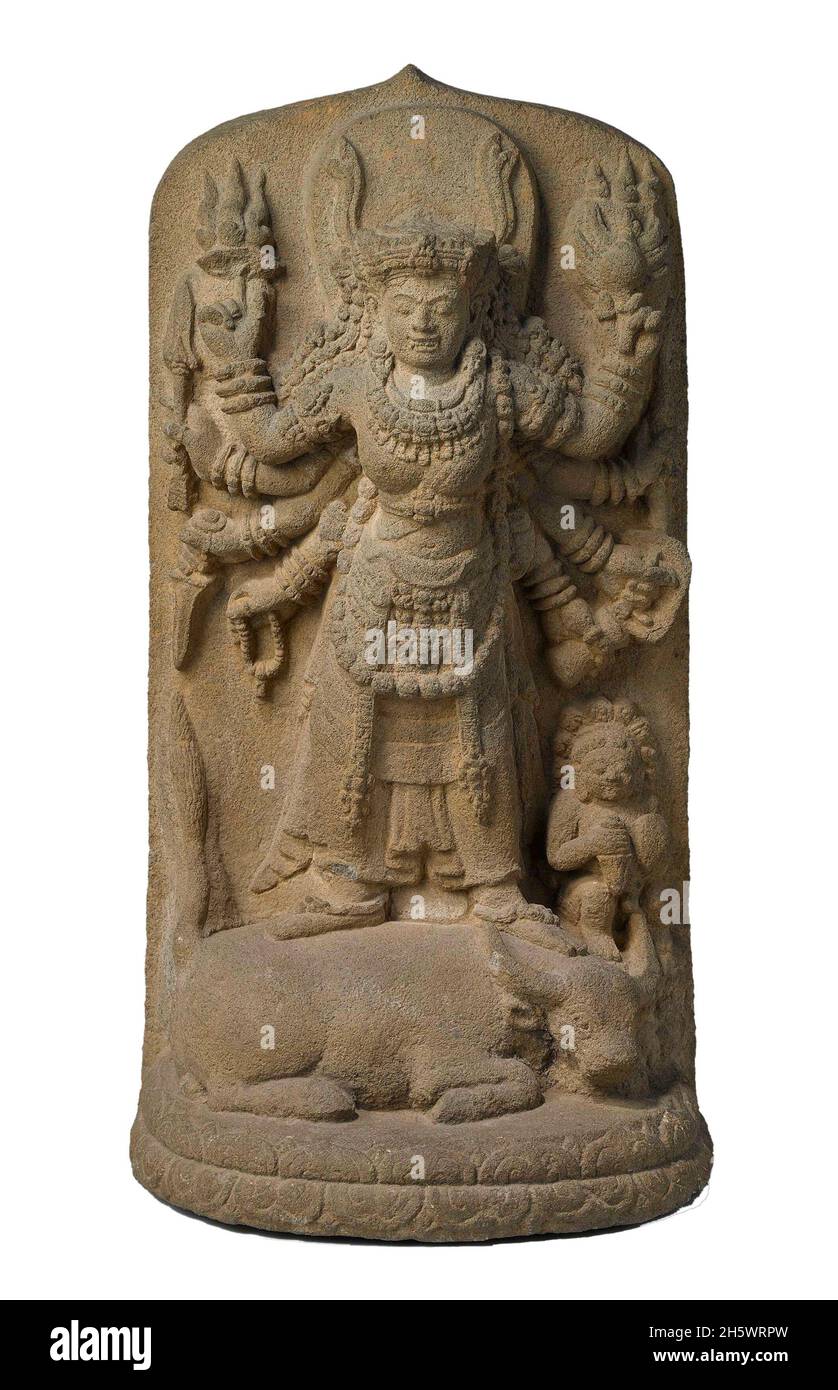 Steinschnitzerei der Hindu-Göttin Durga, die den Büffeldämon tötet. Der Dämon war ein Formwandler. Er trat zuerst als Büffel auf und wurde von Durga enthauptet. Als der Dämon menschliche Gestalt annahm, tötete ihn die Göttin erneut, diesmal mit einem Dreizack. Nach der hinduistischen Mythologie war die Göttin Durga die einzige, die den Dämon aufhalten konnte. In ihren acht Armen trägt sie die Waffen und Symbole der Gottheiten, deren kombinierte Macht sie repräsentiert. Stockfoto