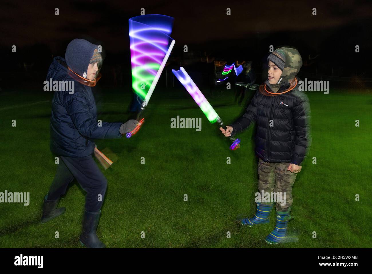 Jungen spielen mit fluoreszierenden Lichtschäbeln bei Guy Fawkes Night, Bonfire Night und Fireworks Night im Südwesten Londons, England, Großbritannien Stockfoto