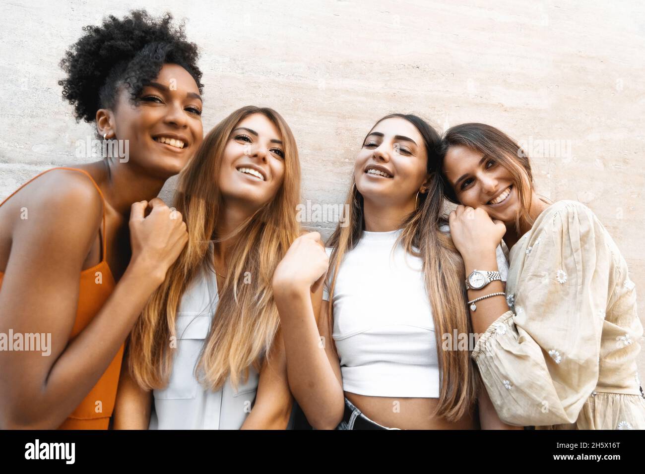 Fröhliche Freundinnen mit Spaß an der Wand stehen - Eine Gruppe fröhlicher junger Frauen versammeln sich sorglos Stockfoto