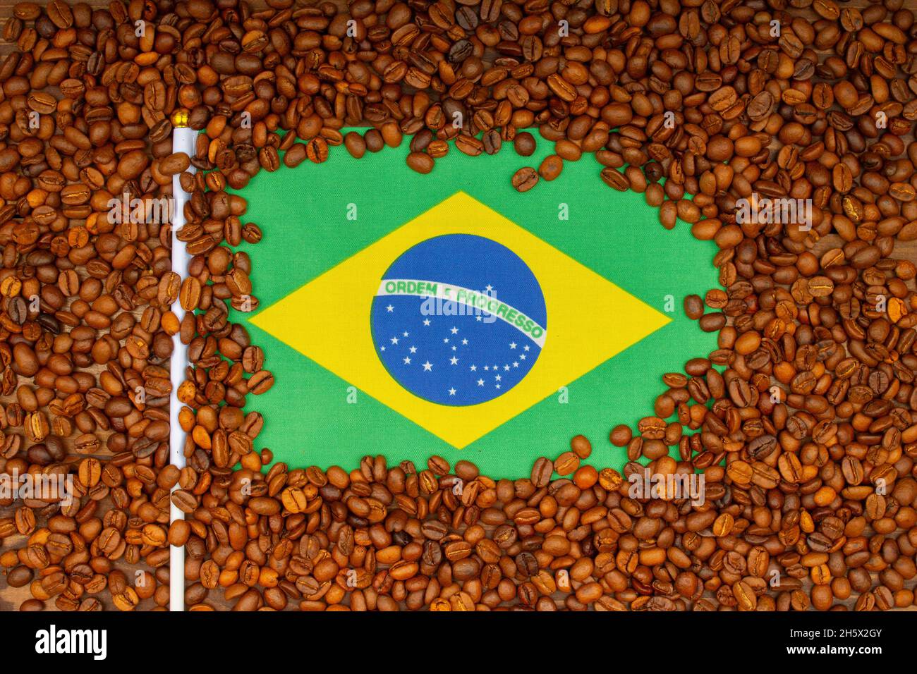 Geröstete Kaffeebohnen und brasilianische Flagge auf dem Tisch. Brasilianisches Konzept zur Erhöhung der Kaffeepreise. Arabica Coffee Futures klettern ab Brasilien. Draufsicht. Nahaufnahme Stockfoto