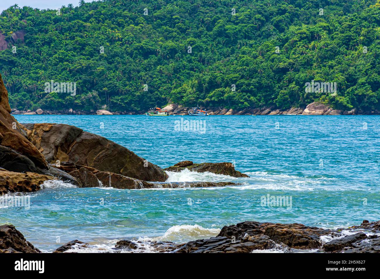 Das Meer von Trindade, Paraty zwischen den Felsen und den dichten und erhaltenen Wald mit Trawlern in ruhigen Gewässern und hellen Farben im Zustand verankert Stockfoto
