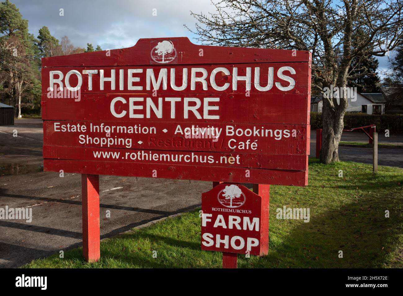 Rot-weißes Schild für Rothiemurchus Center und Hofladen. Sonniger Tag, keine Menschen. Schild isoliert mit verschwommenem Hintergrund von Gras, Bäumen, blauer Himmelswolke Stockfoto