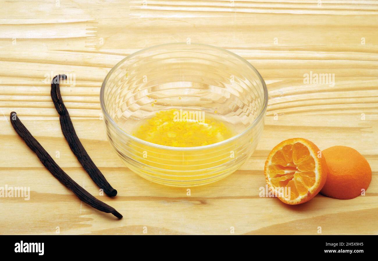 Schüssel mit Eiweiß, Vanille und Mandarinen auf einem Holztisch - Plumcake Maisrezept Stockfoto