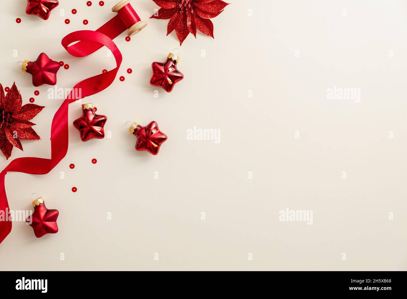Beigefarbener Weihnachtshintergrund mit roten Weihnachtsdekorationen, Band, Konfetti. Flach liegend, Draufsicht, Kopierbereich. Frohes neues Jahr Poster, Grußkarte, Ban Stockfoto