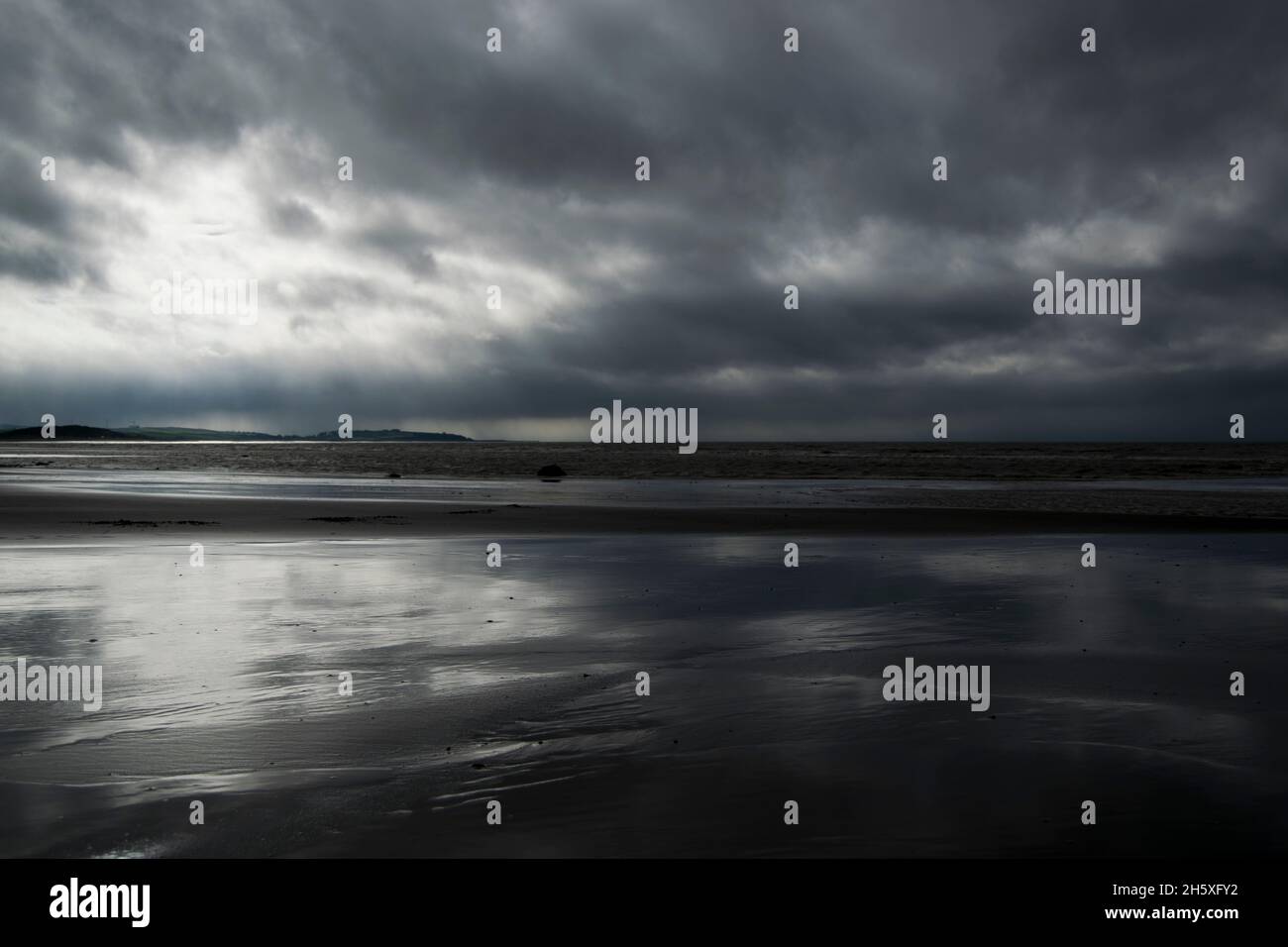 Rückfall stürmischer Wolken im zurücktretenden Gezeitenwasser Stockfoto