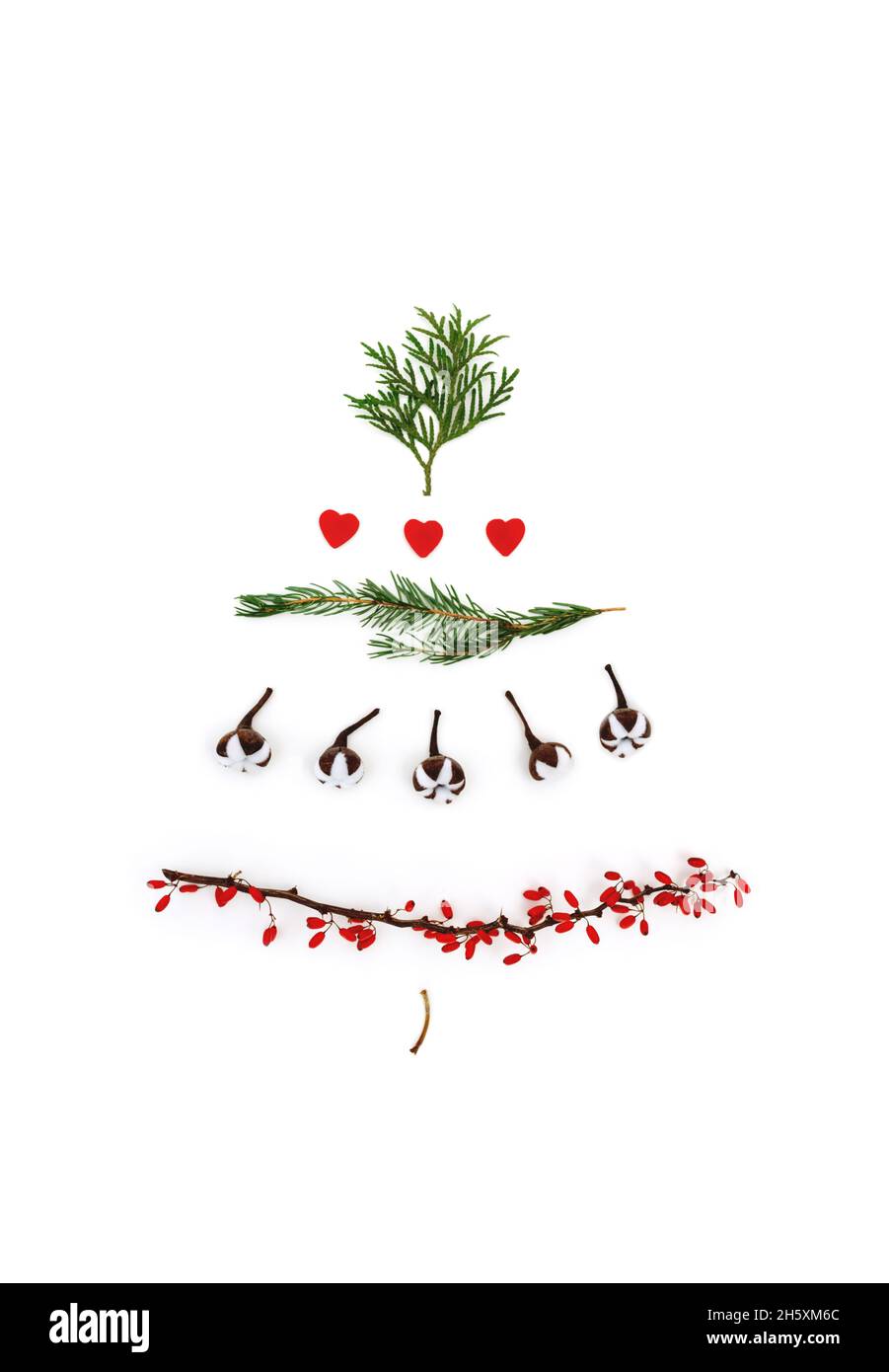 Weihnachten schöner und kreativer Weihnachtsbaum auf weißem Hintergrund als Symbol für Neujahr und frohe Weihnachten aus Zweigen aus Thuja, Baumwolle, roten Herzen und Dogwood-Beeren. Das Konzept einer alternativen Schönheit für den Urlaub. Stockfoto