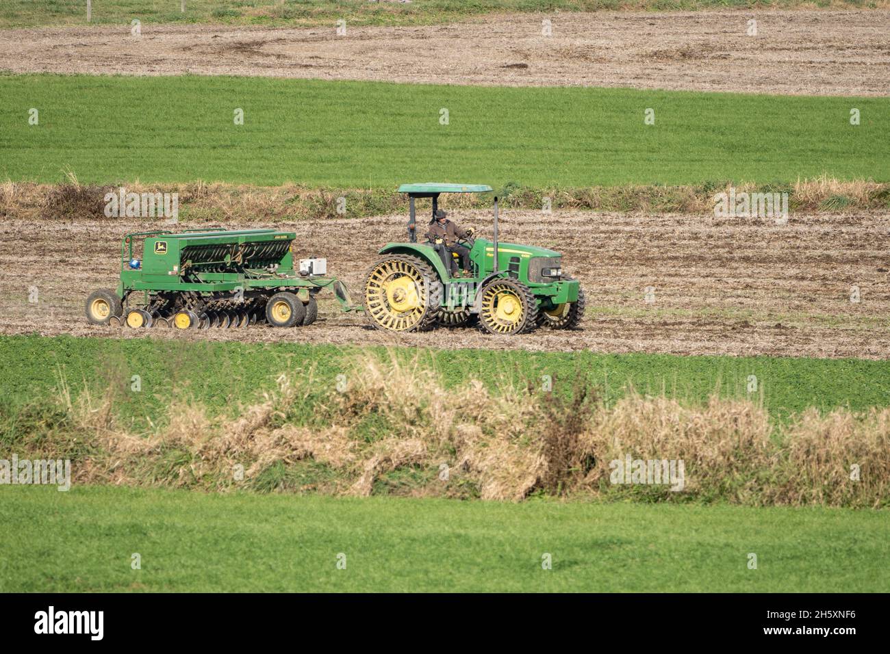 Lancaster County, Pennsylvania, 11. November 2021: Landwirt fährt einen John Deere-Traktor, der Tiller zieht Stockfoto