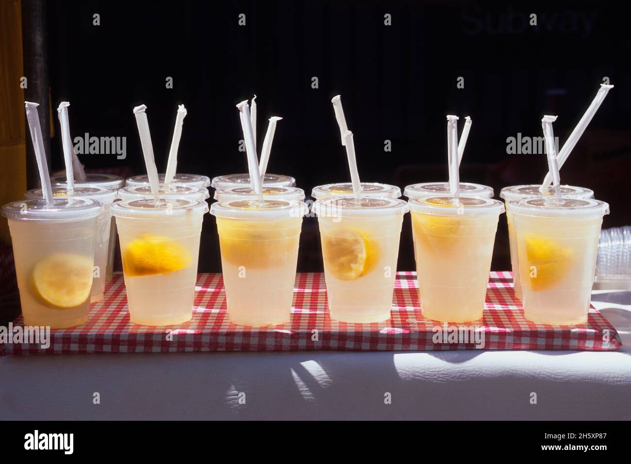 Limonaden- und Zitronenscheiben in Plastikbechern mit Trinkhalmen. Gesundes frisches frisches kaltes Getränk. Kühles Getränk bei heißem Wetter. Keine Personen. Hydrieren Stockfoto