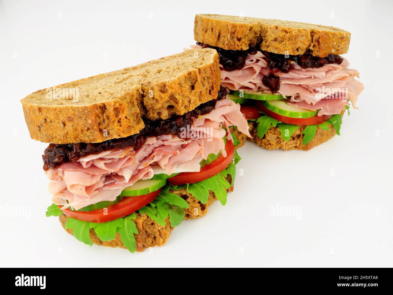 Sandwiches mit Schinken und Salat in knusprigen braunen Brotscheiben mit Gurkenbrötchen Stockfoto
