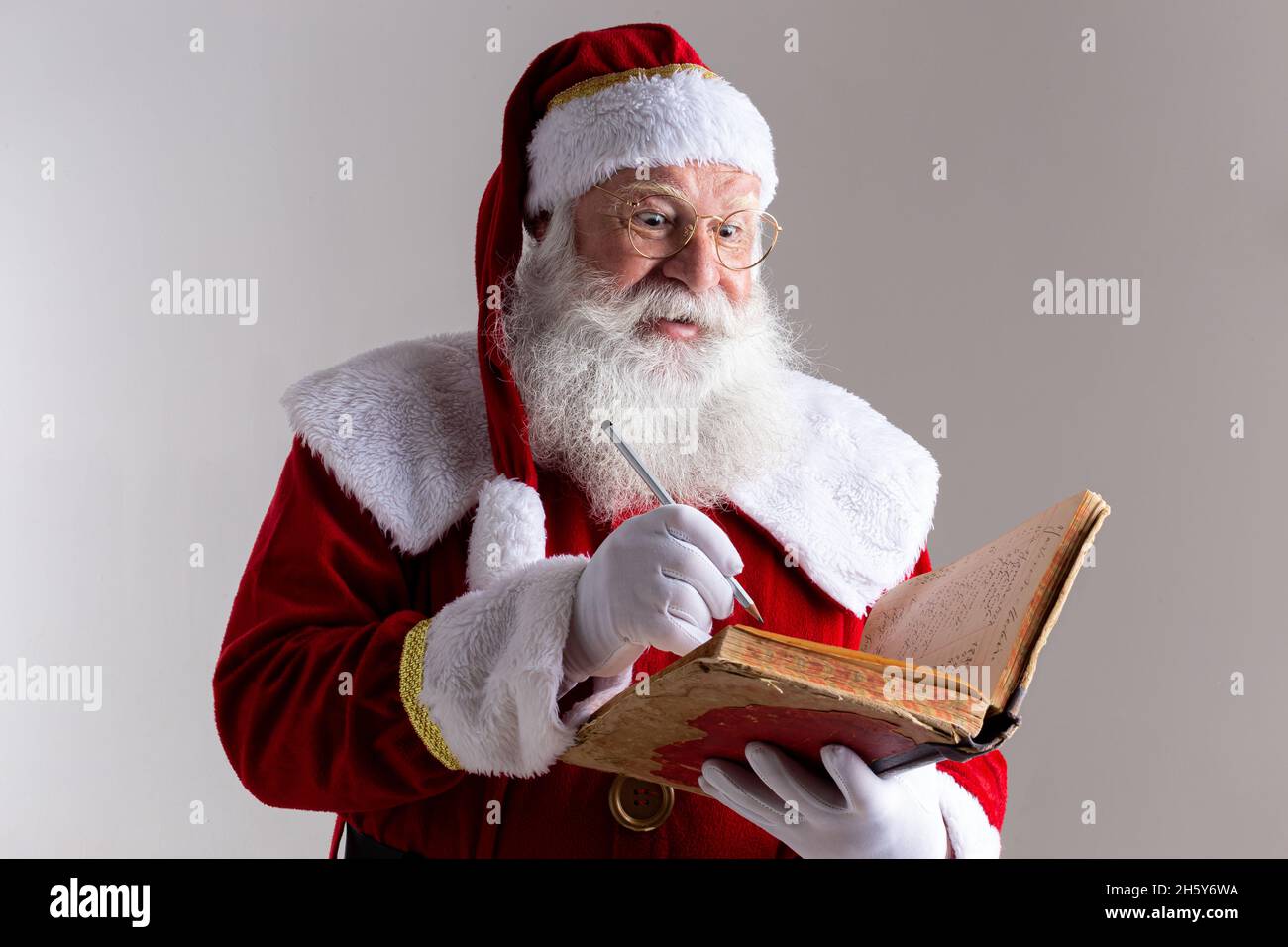 Weihnachtsmann mit einem alten roten Buchumschlag. Das Versetzen von Namen nennt Geschenke für Weihnachten. Weihnachten steht bevor Stockfoto