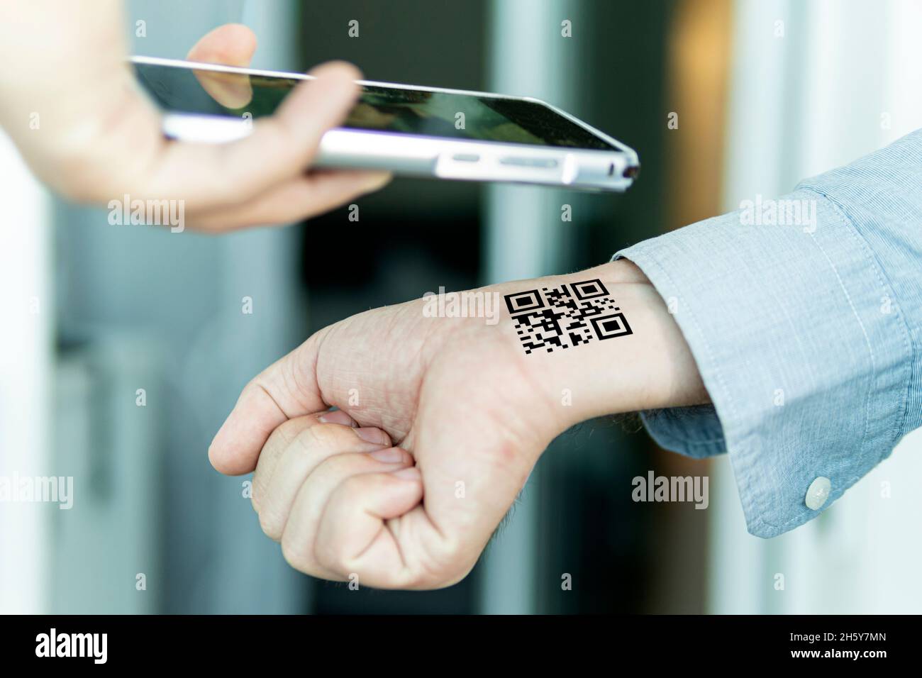 Hand mit qr-Code am Handgelenk. Zukunft der politischen Bevölkerungskontrolle. Chippisierung der Menschen. Scannen Sie den QR-Code mithilfe der mobilen Anwendung. Nachweis der Complet Stockfoto