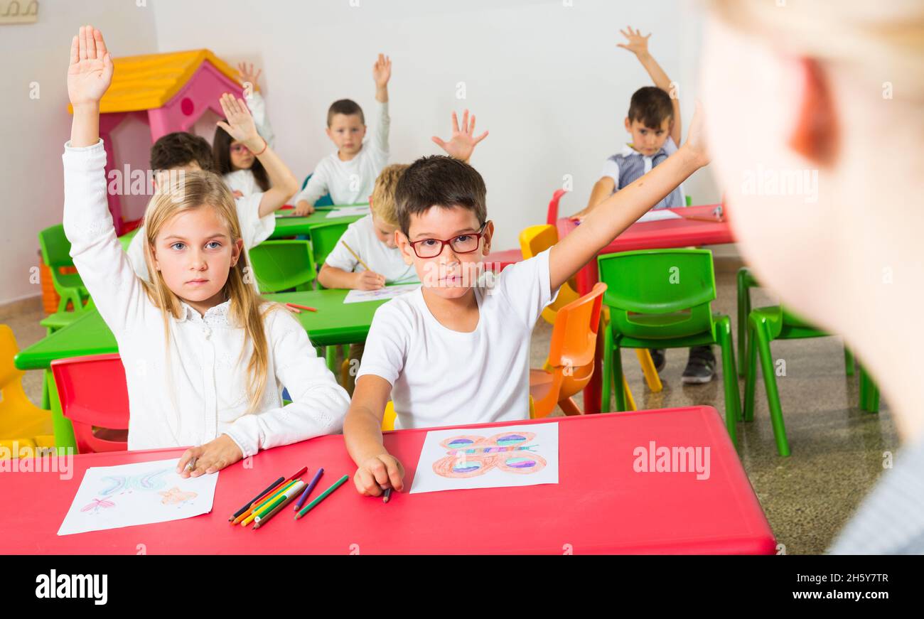 Schüler heben ihre Hände im Klassenzimmer Stockfoto