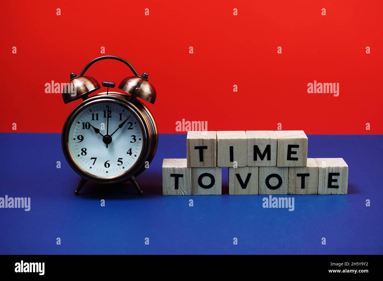 Zeit zum Abstimmen Alphabet Buchstaben mit Wecker auf blauem und rotem Hintergrund Stockfoto
