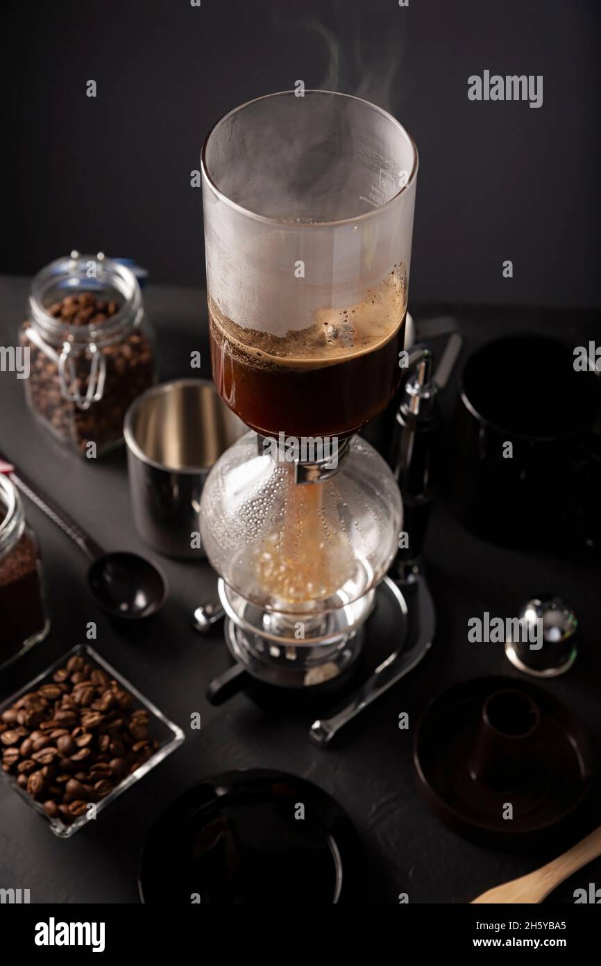 Vakuum-Kaffeemaschine auch bekannt als vac-Topf, Siphon oder Syphon Kaffeemaschine und geröstete Kaffeebohnen auf rustikalen schwarzen Stein Tisch. Stockfoto Vakuum-Kaffeemaschine auch bekannt als vac-Topf, Siphon oder Syphon Kaffeemaschine und geröstete Kaffeebohnen auf rustikalen schwarzen Stein Tisch. Stockfoto