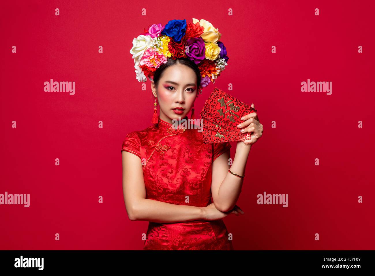 Wunderschöne asiatische Frau in traditioneller orientalischer Tracht mit roten Umschlägen oder Ang Pao in isoliertem Hintergrund für chinesische Neujahrs-Konzepte Stockfoto