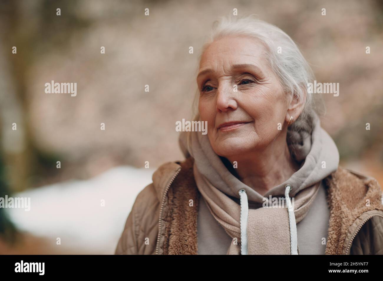 Porträt einer lächelnden grauhaarigen älteren 60 - 70 Jahre alten Frau im Freien Stockfoto