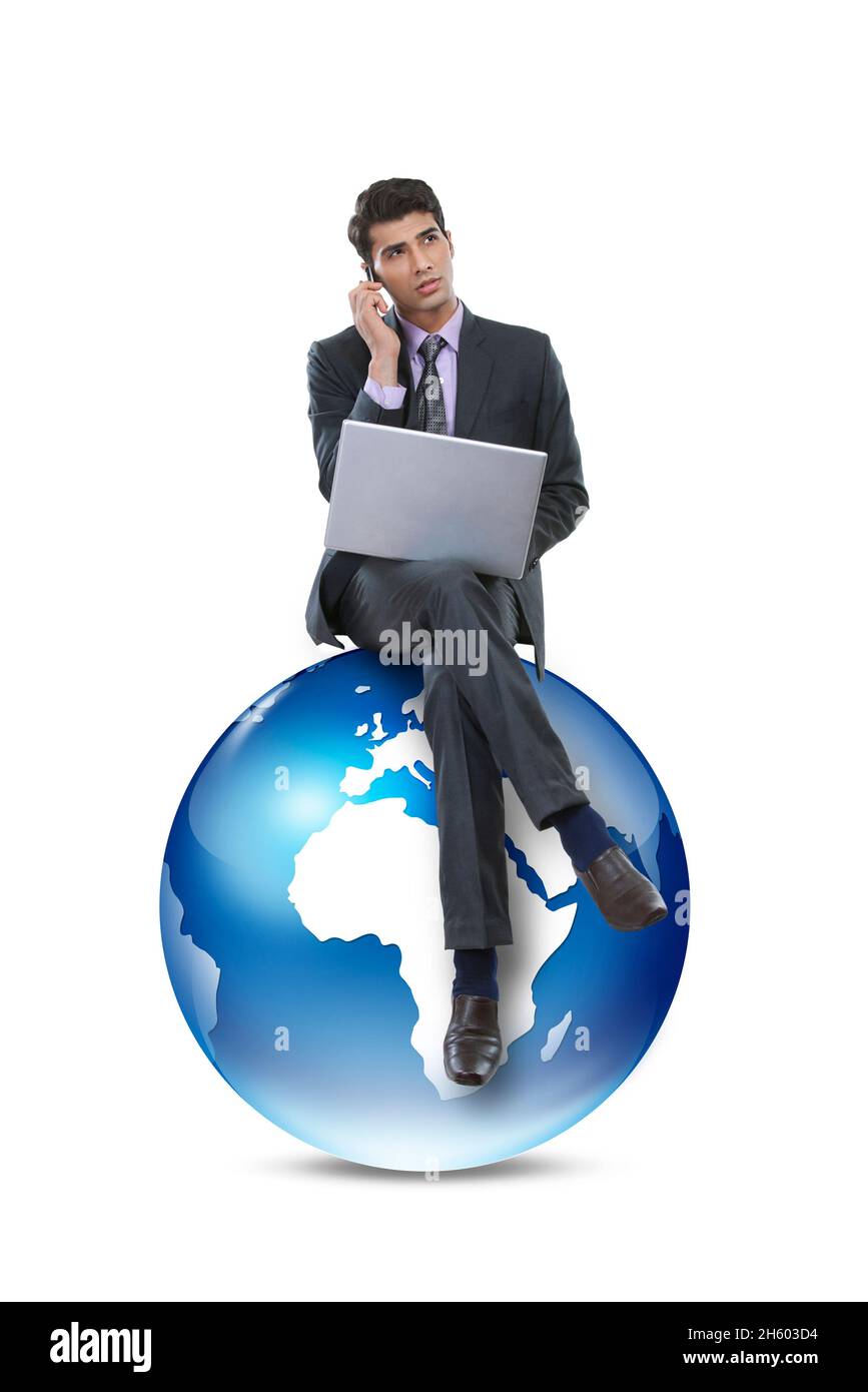 Ein männlicher Unternehmensmitarbeiter, der am Laptop arbeitet und am Telefon sitzt und auf grafischer Erde sitzt. Stockfoto