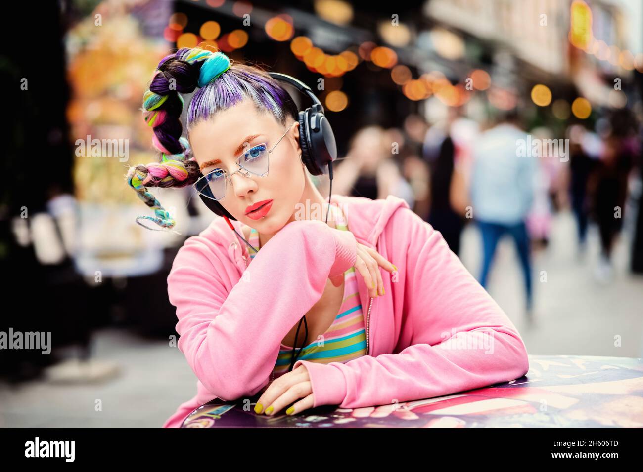 Coole, flippige Hipster junge Frau mit Piercings und trendigen Sonnenbrillen, die Musik auf Kopfhörern im Freien hören - verrückter Look und Haare Stockfoto
