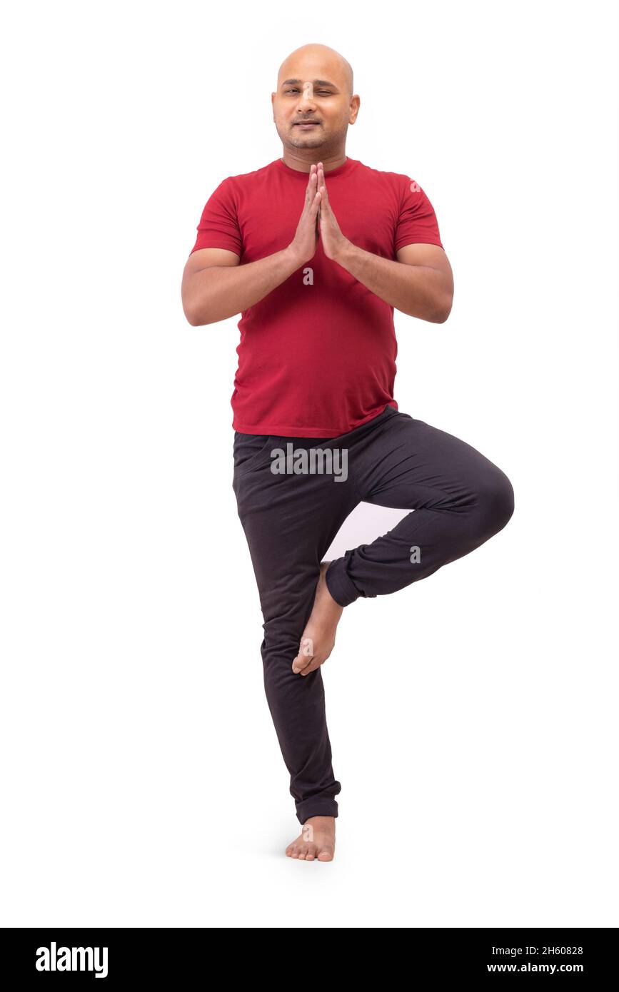 Porträt eines kahlen Mannes, der vor weißem Hintergrund steht und Yoga macht. Stockfoto