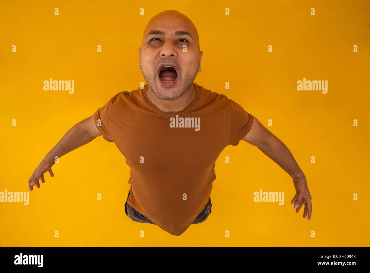 Porträt eines kahlen Mannes, der vor schlichtem Hintergrund steht und schreit. Stockfoto