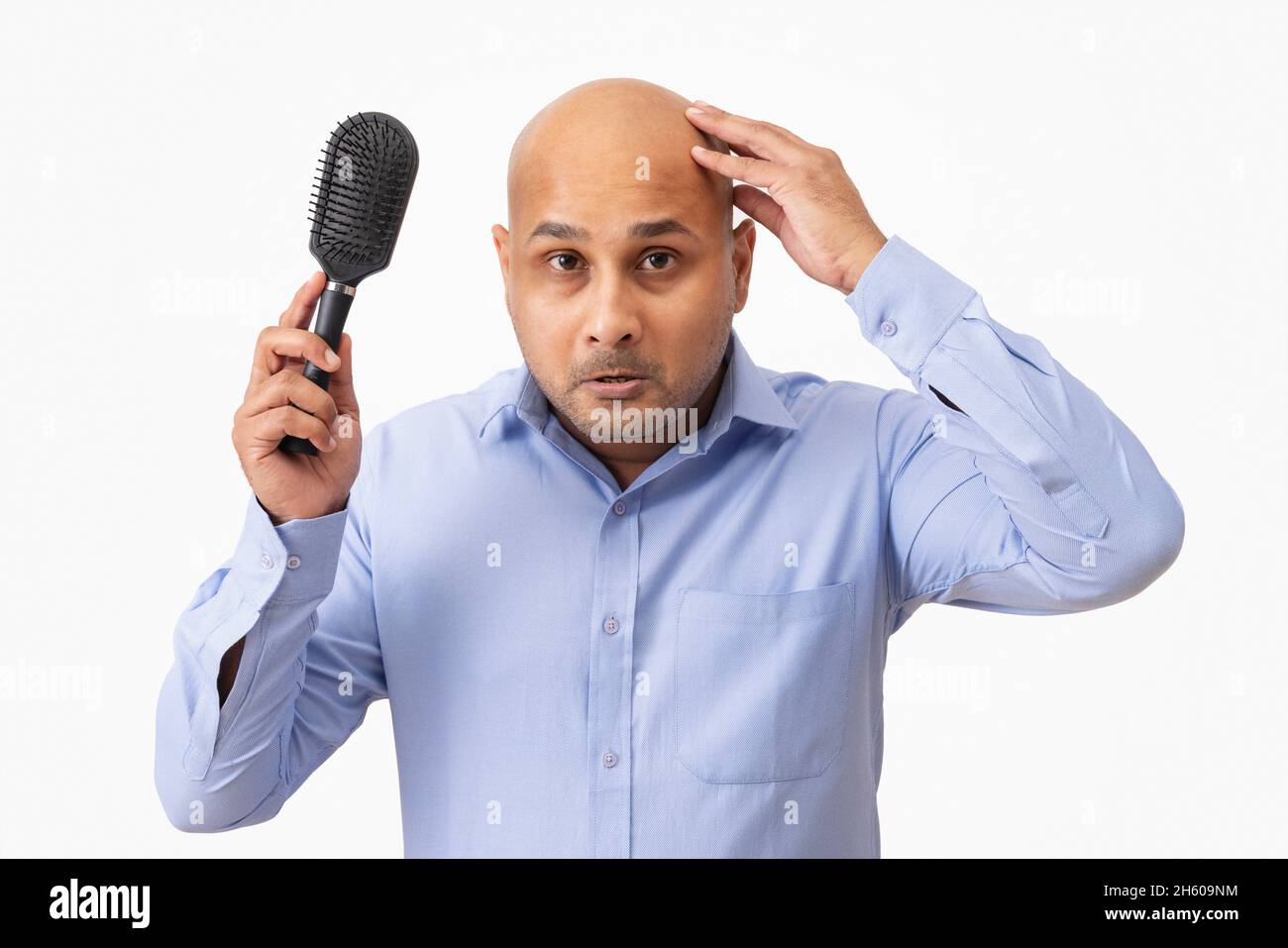 Porträt eines kahlen Mannes, der seinen rasierten Kopf traurig berührt, während er Kamm in der Hand hält. Stockfoto