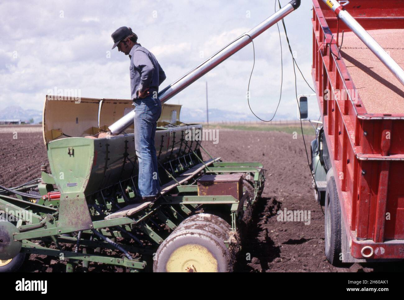 Landwirt füllt Sämaschine auf Traktor, Mai 1977 Stockfoto