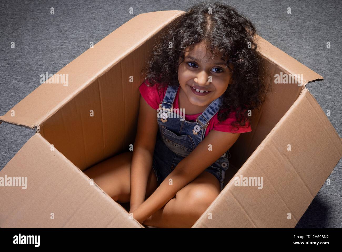 Nettes Mädchen, das zum Zeitpunkt des Spielens in der Box sitzt Stockfoto