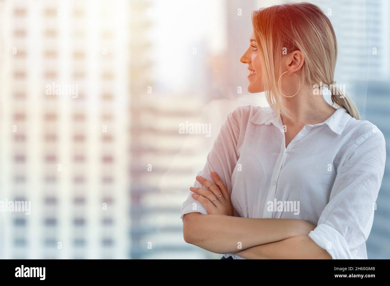 Geschäftsfrau, die aus dem Fenster schaut, lächelt glücklich für das Vision-Konzept der Führungskraft Stockfoto