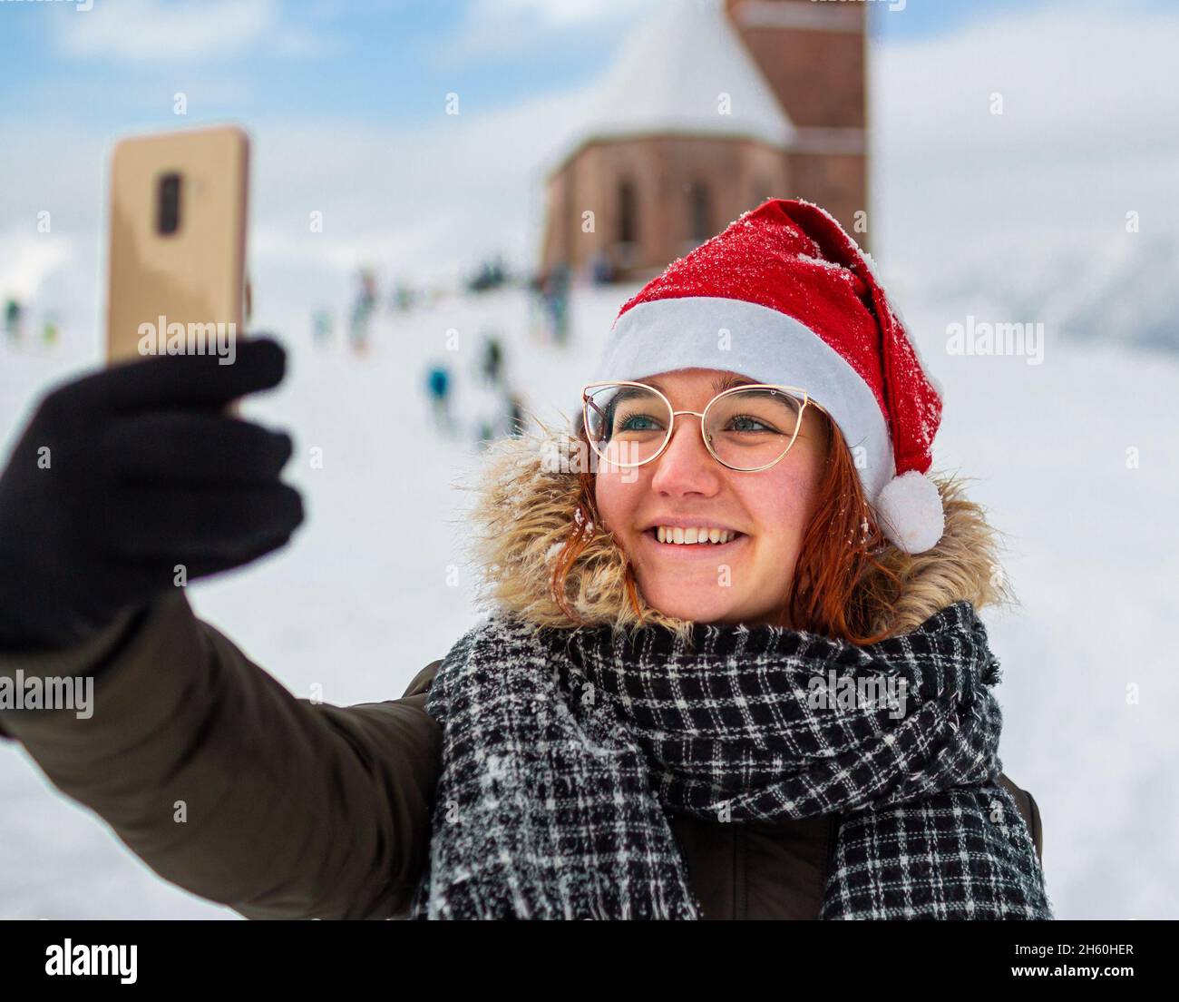 Junge Frau lächelt und nimmt ein Selfie in der Winterlandschaft mit verschwommenem Hintergrund Stockfoto