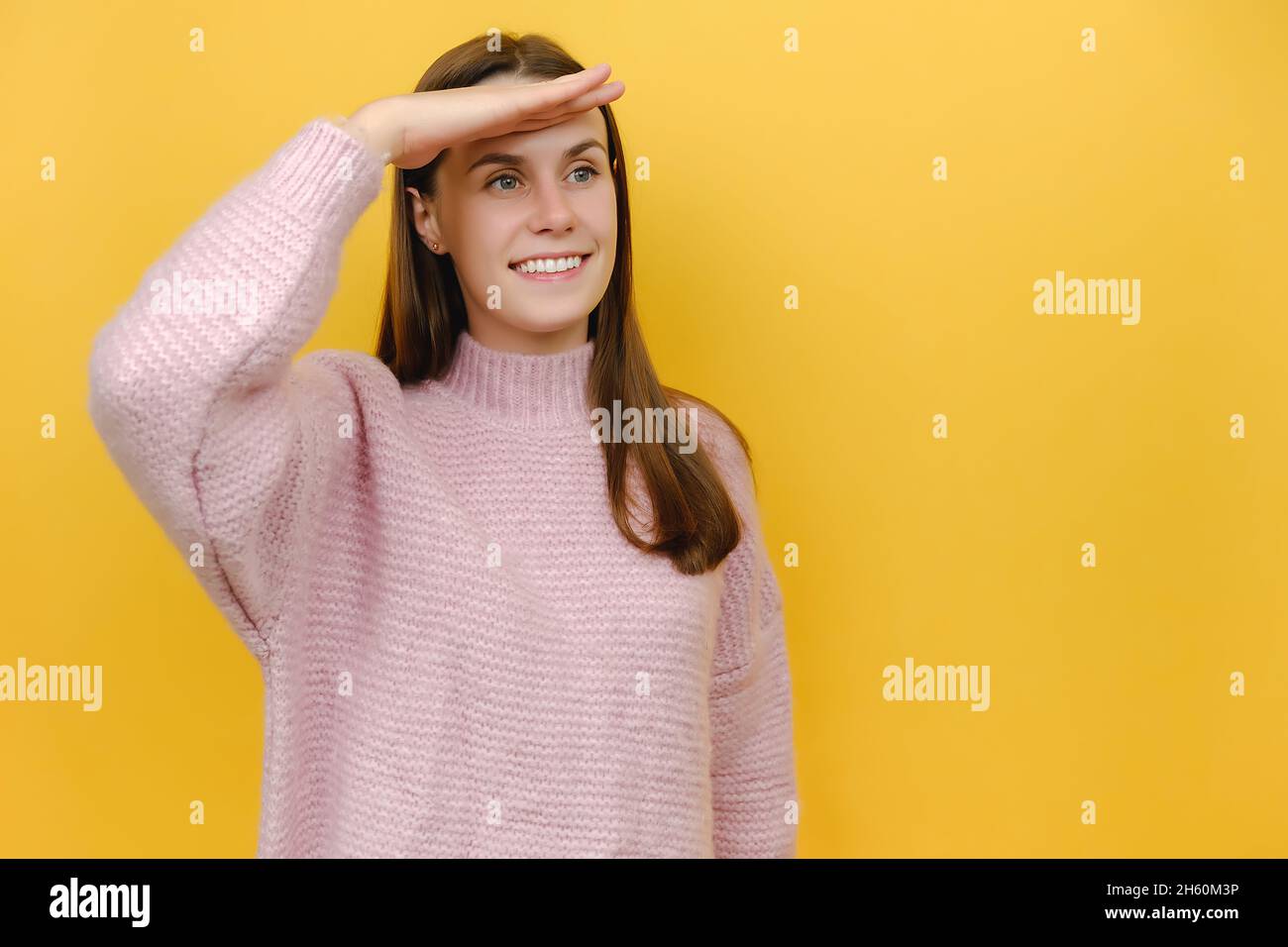 Porträt eines lächelnden optimistischen Warten traumartig glücklich nette junge Frau 20s mit der Hand an der Stirn, weit weg von der Ferne, in rosa gestrickt gekleidet Stockfoto