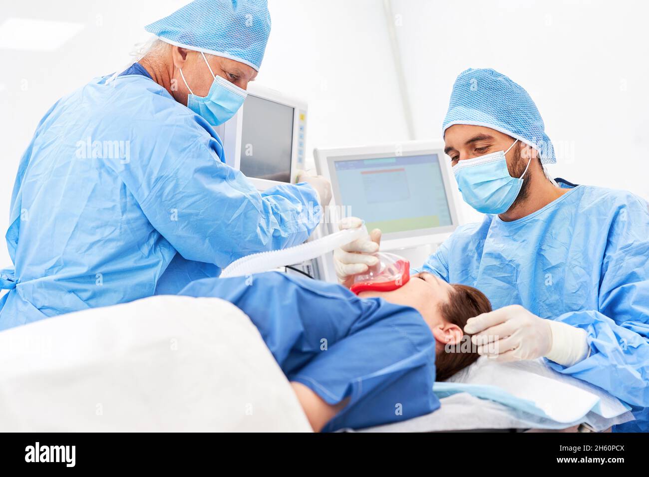 Chirurg und Anästhesist arbeiten zusammen, um den Patienten vor der Operation zu naresisieren Stockfoto