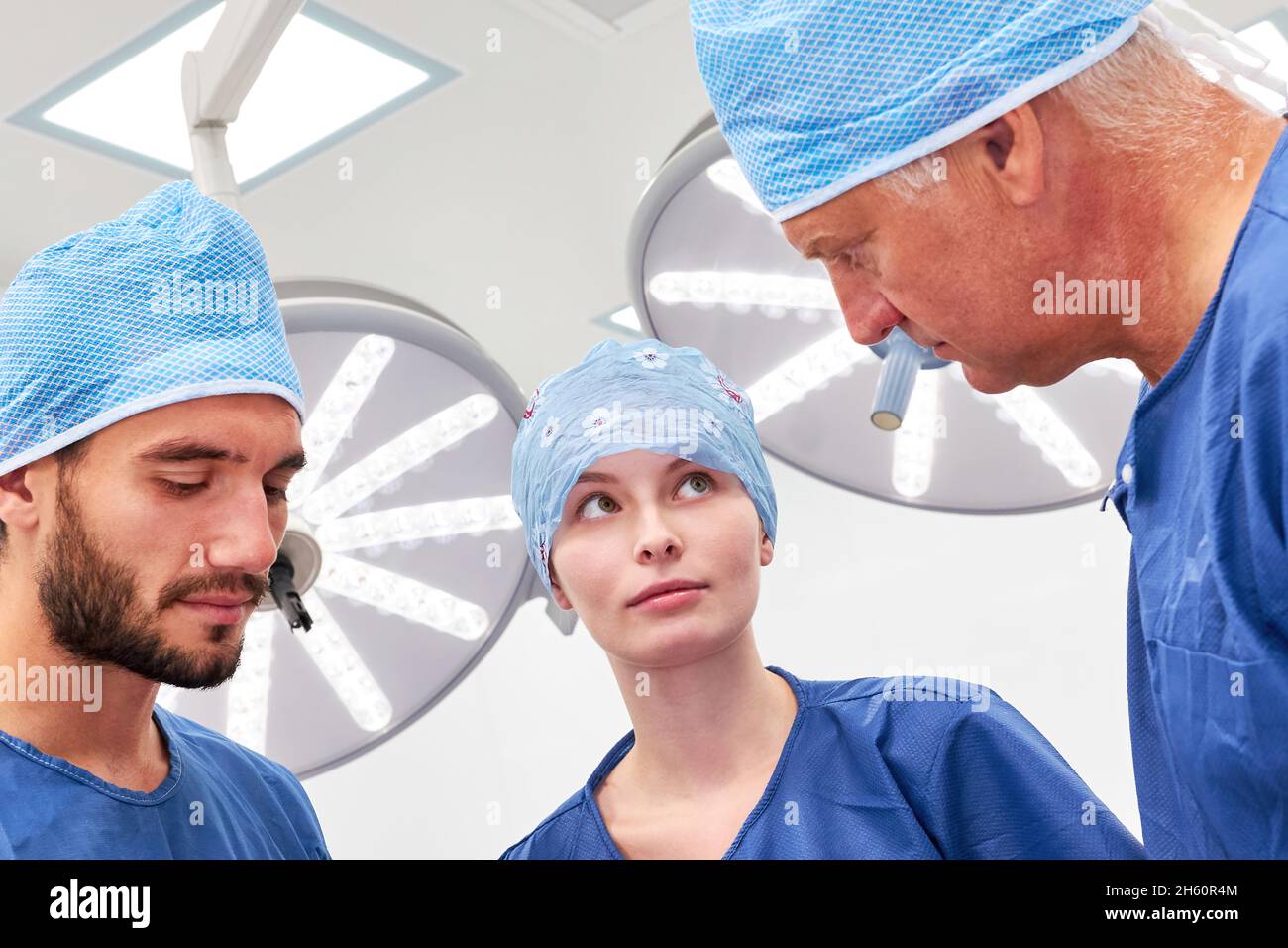 Ärzte als Team von Chirurgen in Kleidern und Hauben bei der Besprechung und OP-Planung in der Chirurgie Stockfoto