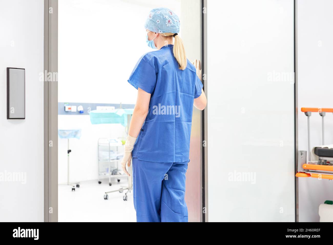 Die junge Frau als OP-Krankenschwester oder Chirurg steht müde und ausgebrannt vor dem Operationssaal Stockfoto