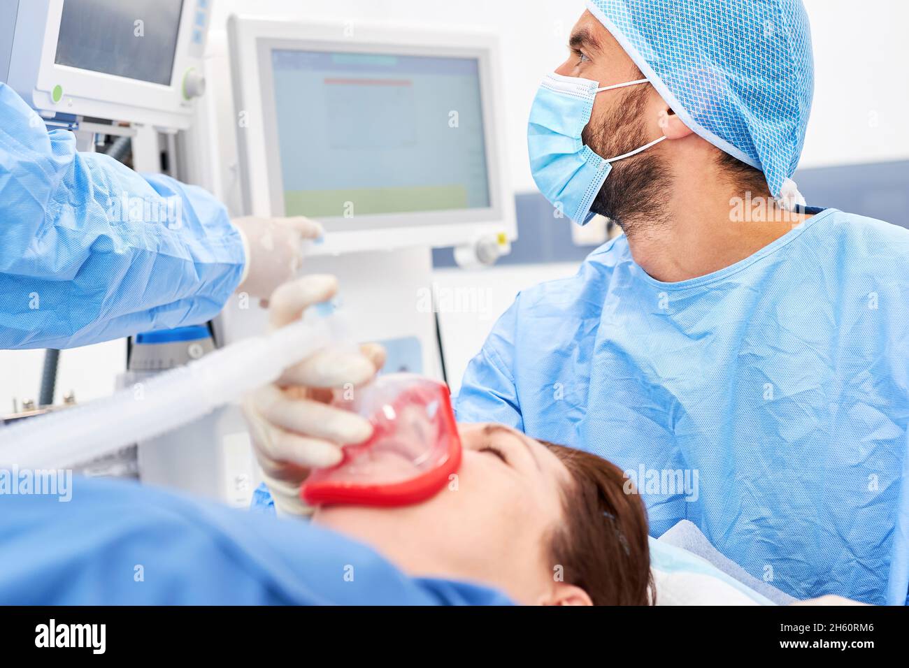 Anästhesist beobachtet den Monitor am Beatmungsgerät, während der Patient naresisiert wird Stockfoto