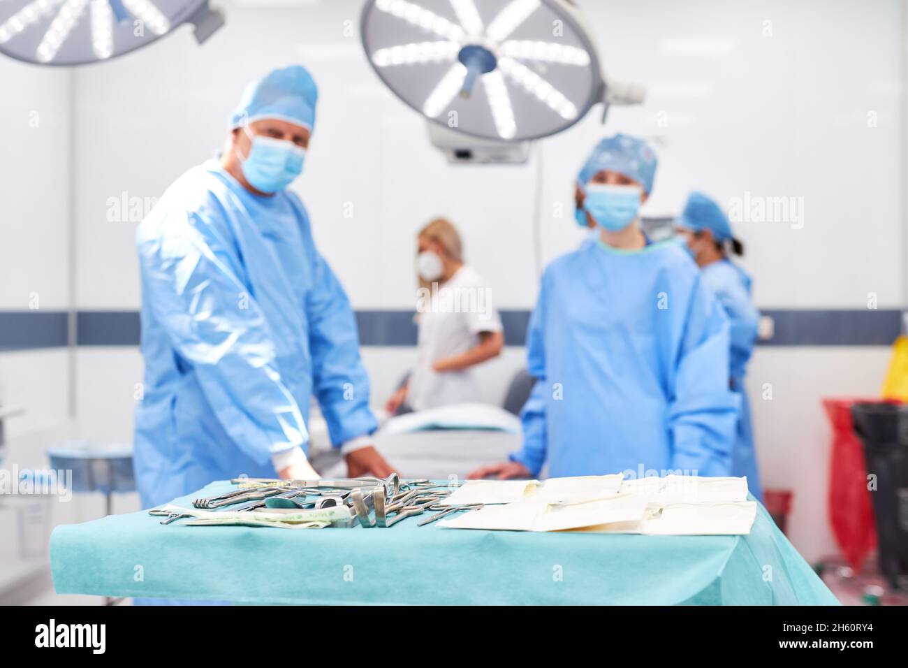 Medizinisches Team in der Chirurgie in Schutzkleidung im Operationssaal mit chirurgischen Instrumenten im Vordergrund Stockfoto