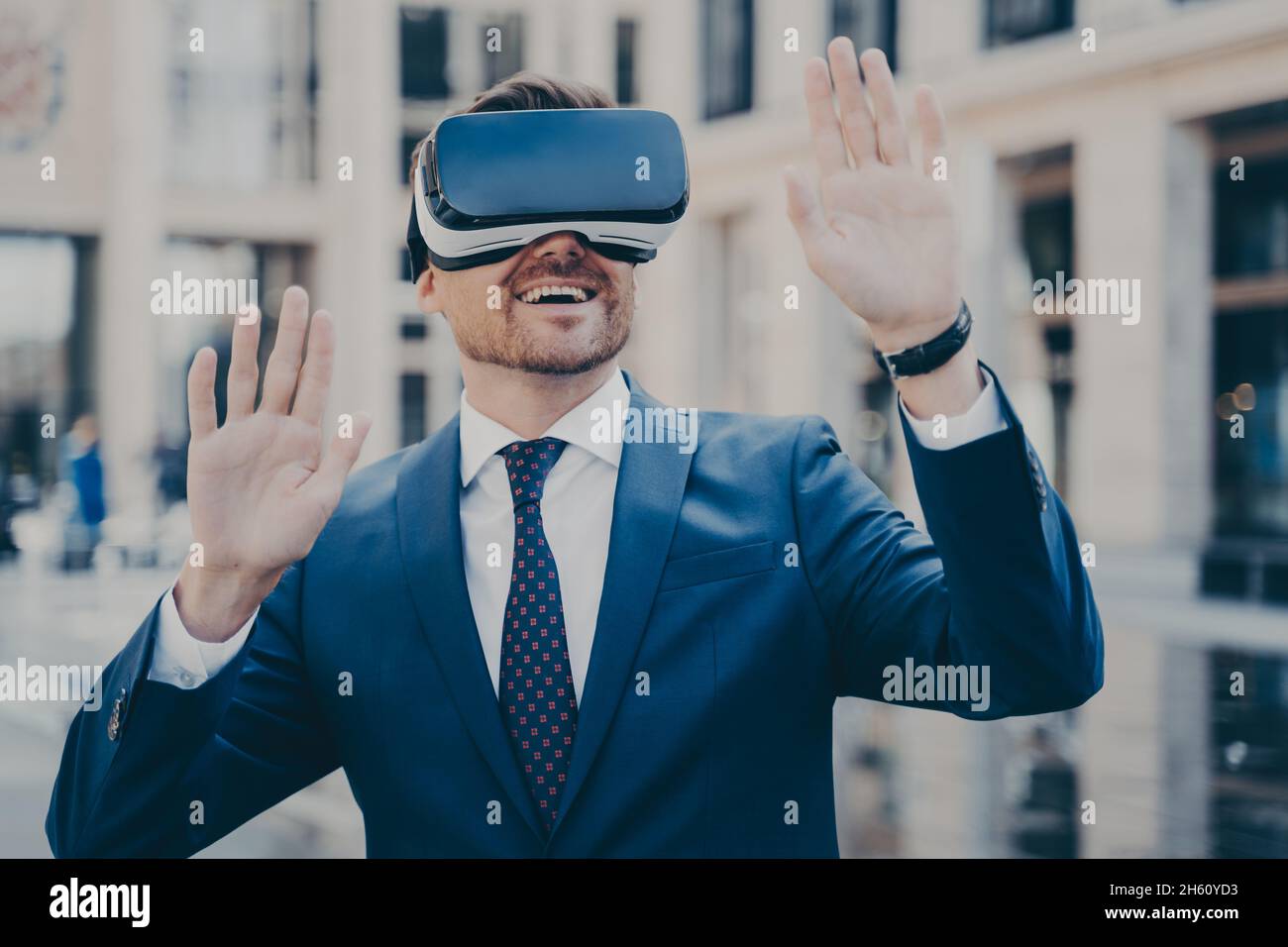 Büroangestellter im Anzug erkundet die virtuelle Welt mit einer VR-Brille und entspannt sich im Freien Stockfoto