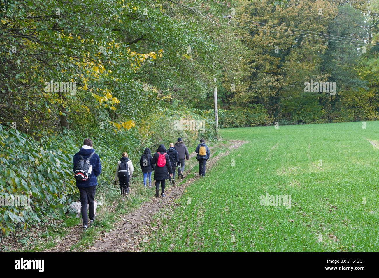 Eine Gruppe von Menschen, die auf einem gesponserten Spaziergang für wohltätige Zwecke durch ein Feld in der englischen Landschaft wandern. Teamaktivität, durch die britische Außenluft. Stockfoto