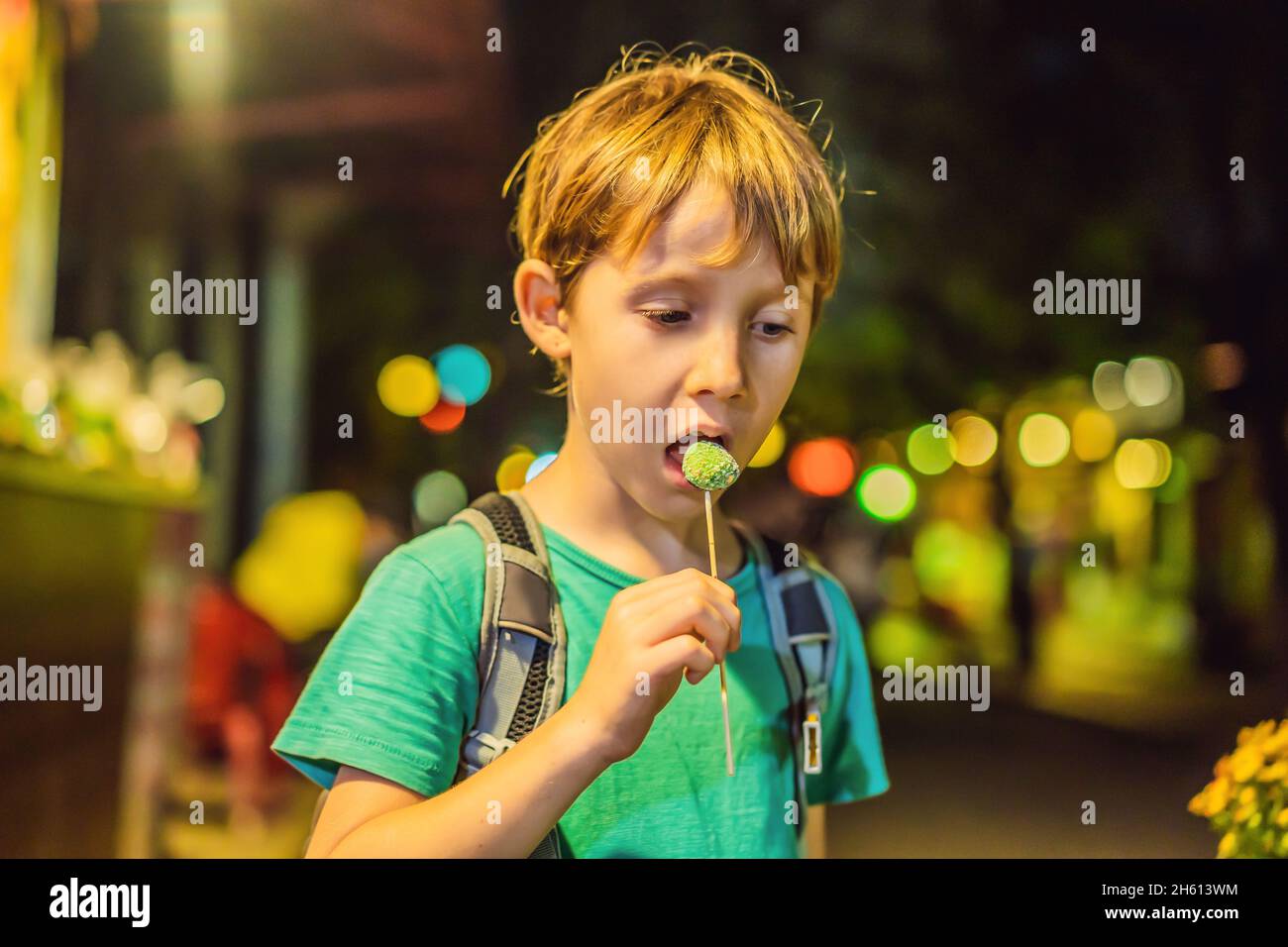 Der Junge isst Maisstäbchen, die mit flüssigem Stickstoff verschüttet sind Stockfoto